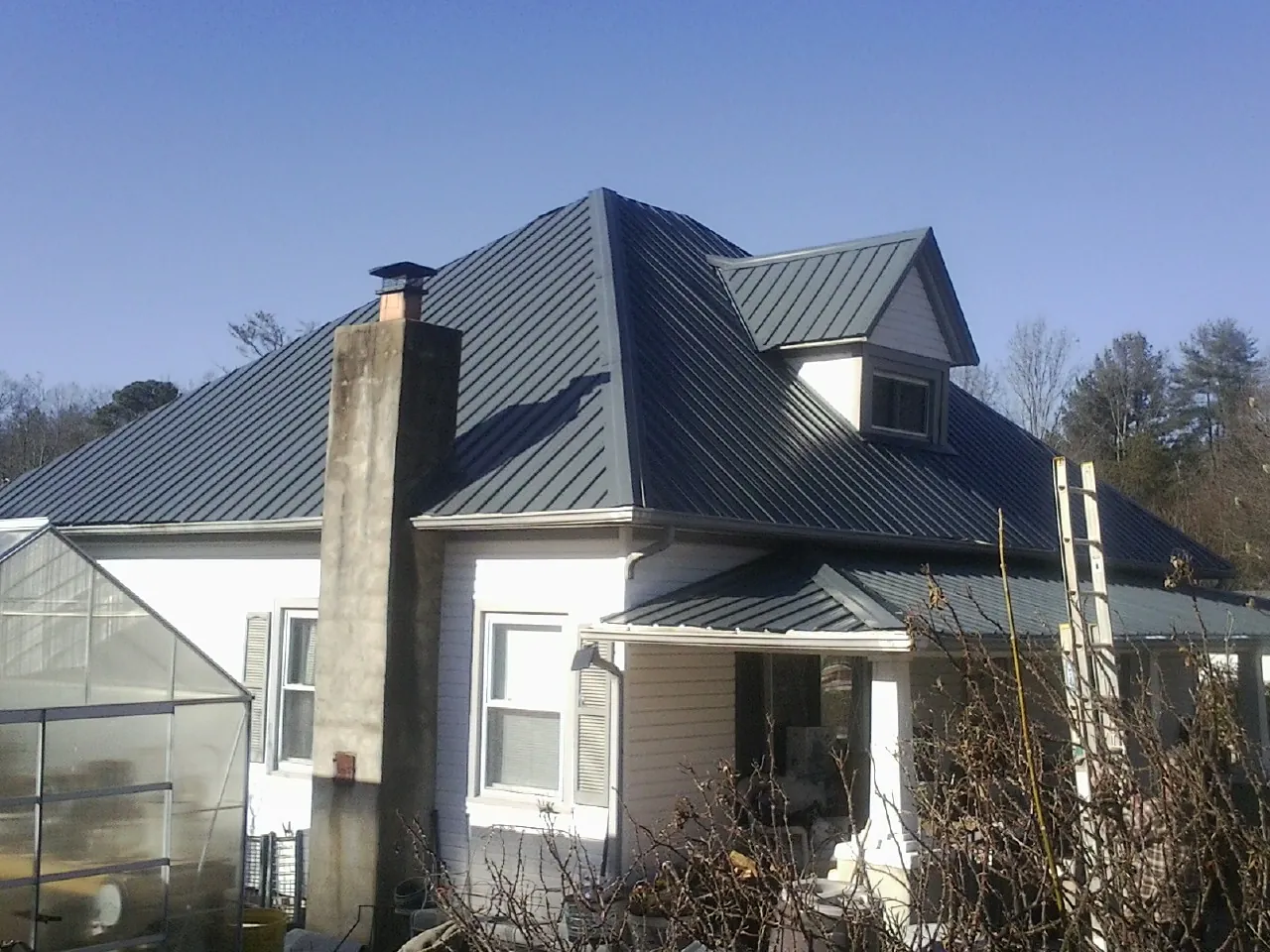 Dark blue standing seam metal roof on a white farmhouse with dormer — Slate & Tile Roof Repair by Roofing Brothers in Scotts Mills