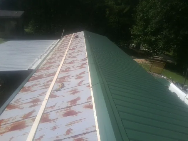 Old rusted panels beside newly installed green metal roofing — Wind Damage Roof Repair by Roofing Brothers in Scotts Mills
