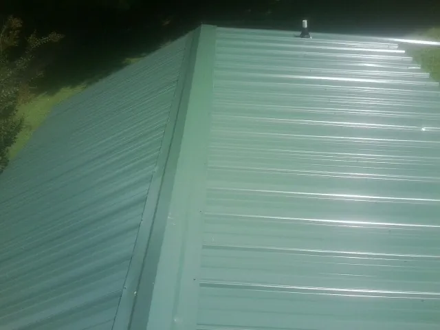 New green metal panels meeting at the ridge of a roof — Flat Roof Repair work by our crew in Scotts Mills