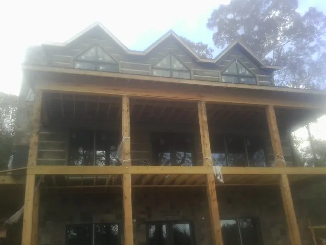 Dormers and porch framing on a large log home under construction — Roof Coating work by our crew in Scotts Mills