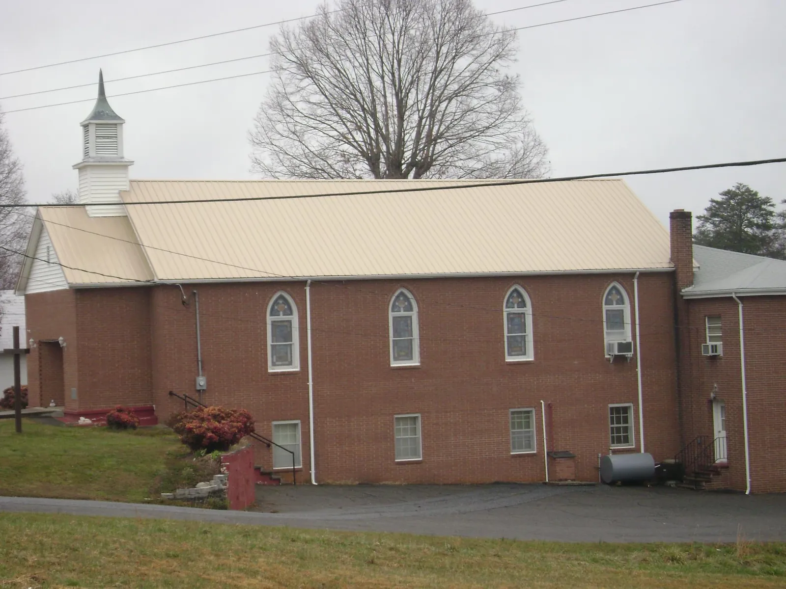 New tan metal roof on a brick church with a white steeple in Scotts Mills