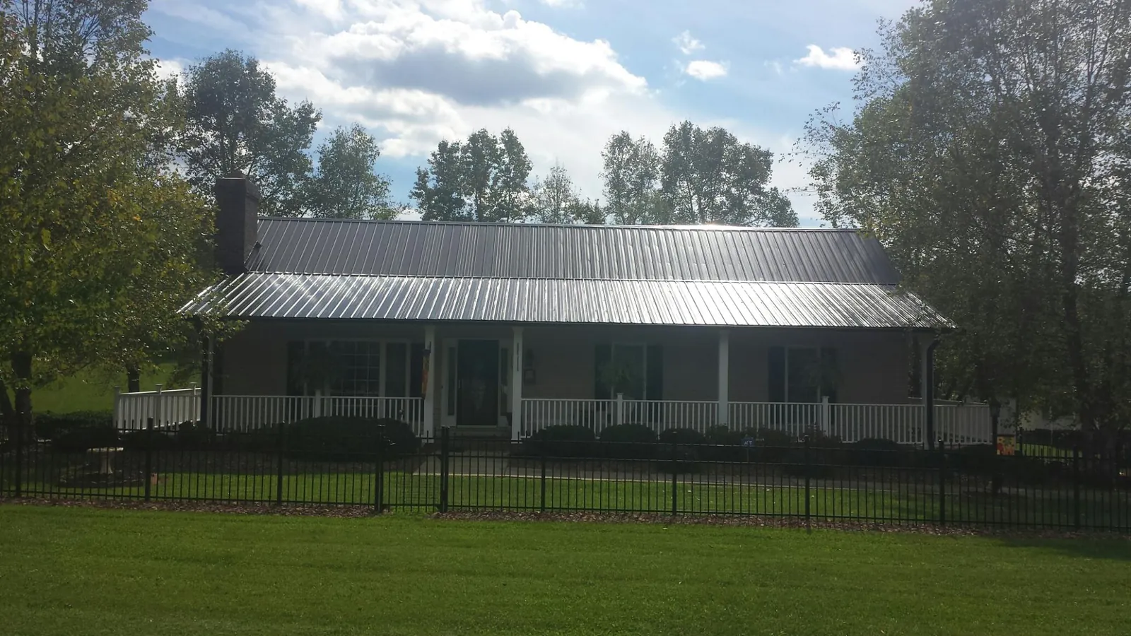 Gray metal roof on a brick ranch with a full width front porch — Gutter Guard Installation work by our crew in Scotts Mills