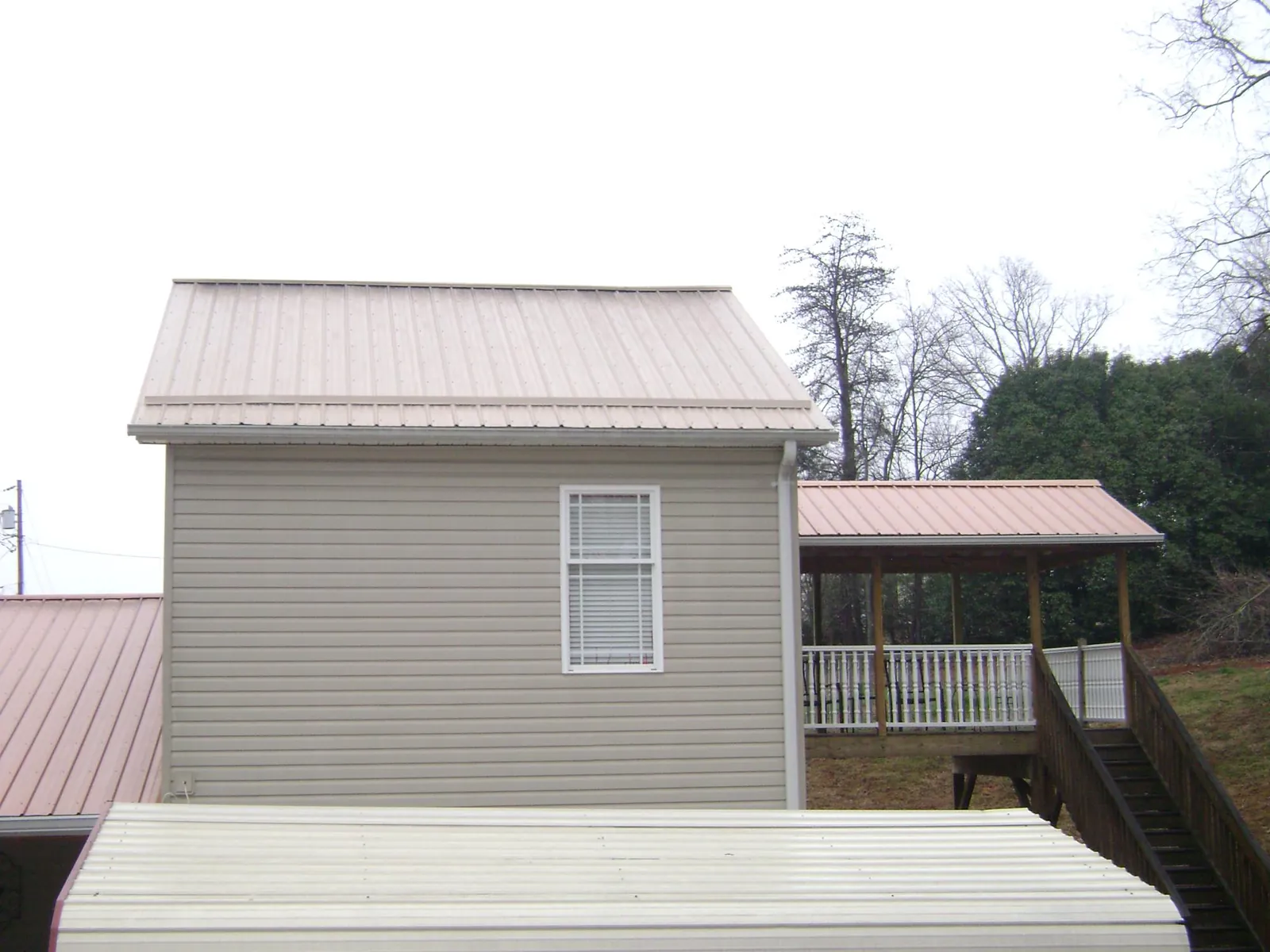 Tan metal roofs on a two story addition and attached porch, from a Roof Replacement job in Scotts Mills