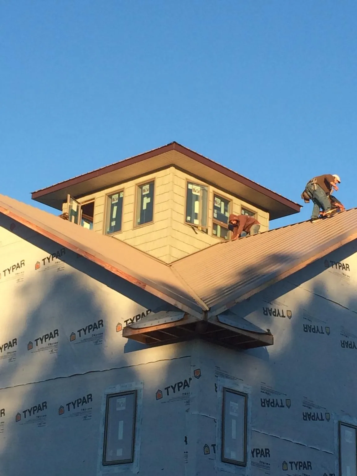 Roofers working around a rooftop cupola on a new metal roof at sunset — Roof Waterproofing in Scotts Mills by Roofing Brothers